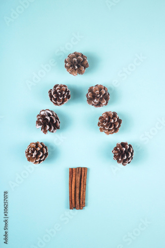 Cinnamon cones and sticks are laid out in the form of a minimalistic Christmas tree on a blue background. Creative flat lay, top view, copu space. photo