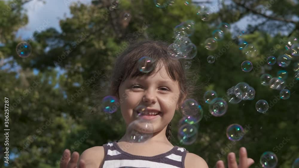 Playful bubbles. Happy little girl playing with soap bubbles on a summer sunny day. Playful bubbles. Happy little girl playing with soap bubbles on a summer sunny day.
