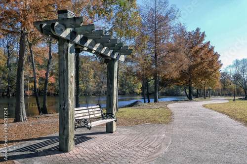 Vacant swing and walkway along the shore of a river of a beautiful autumn day