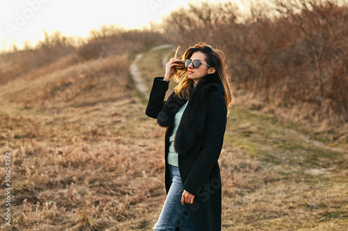 Styilish fashion model in sunglasses and coat. Outdoor shot beautiful young woman.  © EvgL