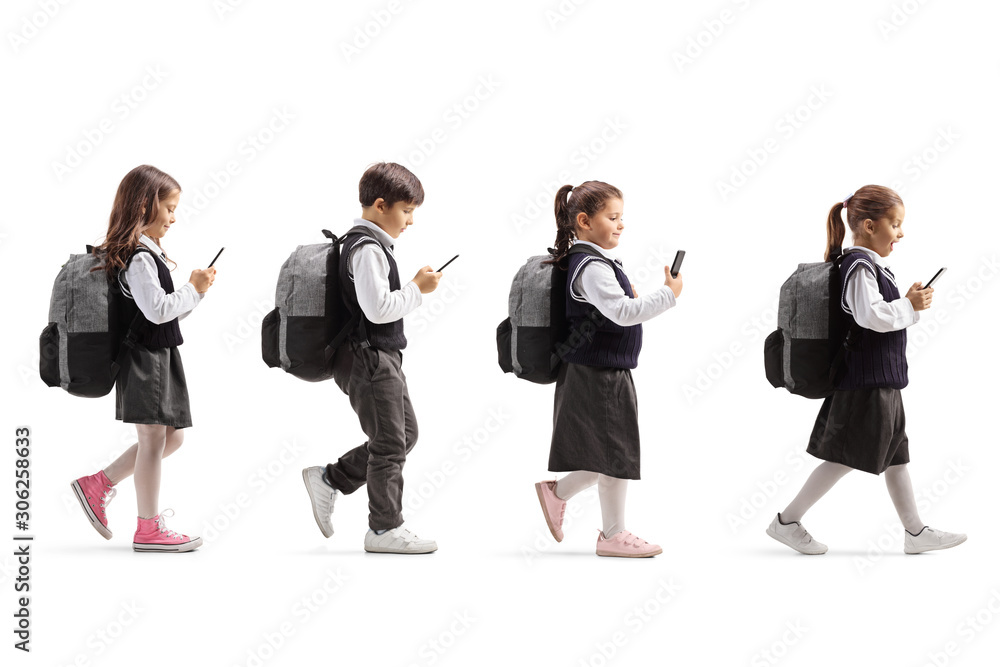 Three schoolgirls and one schoolboy with mobile phones walking in line Three schoolgirls and one schoolboy with mobile phones walking in line