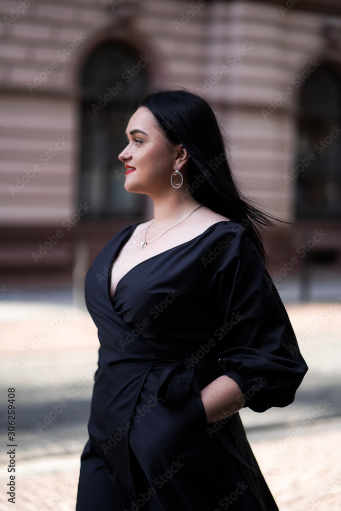 Autumn fashion outdoor. The girl with red lips in fashionable stylish black dress, autumnal lifestyle on the background of blurry yellow-green trees in the park. Vertical Autumn fashion outdoor. The girl with red lips in fashionable stylish black dress, autumnal lifestyle on the background of blurry yellow-green trees in the park. Vertical