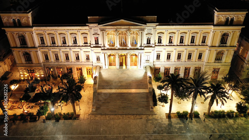 Aerial drone night shot of neoclassic landmark building of Ermoupolis town city hall in Miaouli square, Syros or Siros island, Cyclades, Greece photo