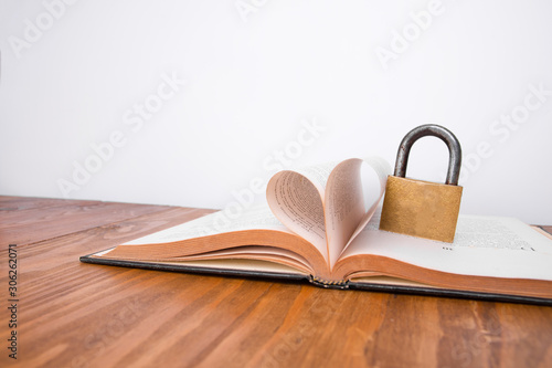 Old book and padlock on a wooden table and a white background