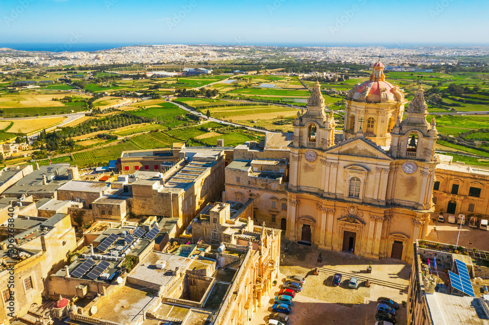 The main church and square in Mdina city - old capital of Malta. Aerial nature landscape, sunny day, blue sly, winter, a lot of green grass, field on background. Malta island