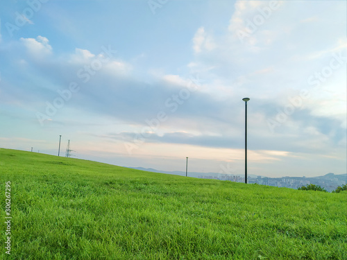 landscape sloping glade in the Park with a blue cloudy sky and the city in the distance