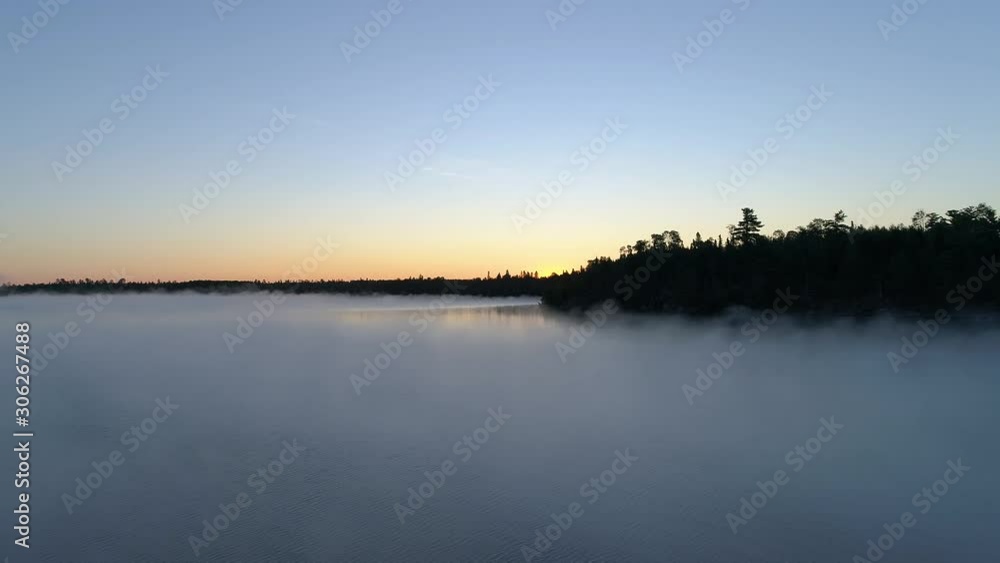 4K aerial reverse flight over a fog covered lake on a misty fall morning in Northwest Ontario, Canada. 4K aerial reverse flight over a fog covered lake on a misty fall morning in Northwest Ontario, Canada.