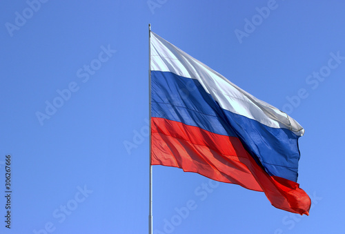 Russian state flag waving in the wind close-up. Photo taken against a blue-gray sky.