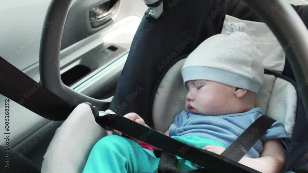 Adorable baby boy is sleeping in baby safety seat in the driving car. Slow motion Adorable baby boy is sleeping in baby safety seat in the driving car. Slow motion
