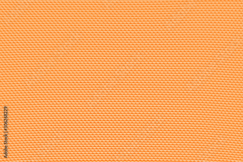 Light orange background from a textile material with pattern, closeup. Structure of bittersweet color fabric with punching texture. Perforated cloth backdrop..