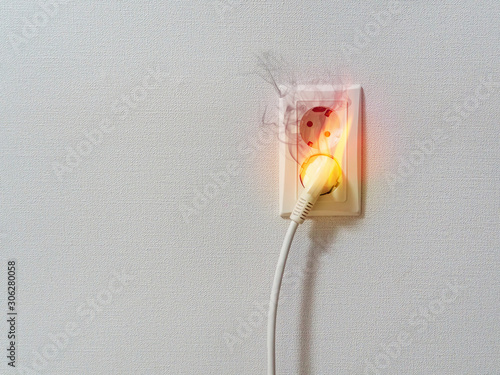 Electric short circuit causing fire on plug socket. Fire and smoke on electric wire plug.