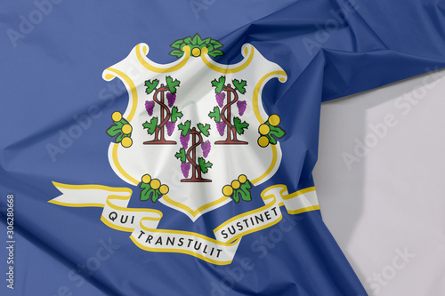 Connecticut fabric flag crepe and crease with white space. Three bunches of grapes on royal blue color. text below "Qui Transtulit Sustinet", Latin for "He who transplanted sustains"