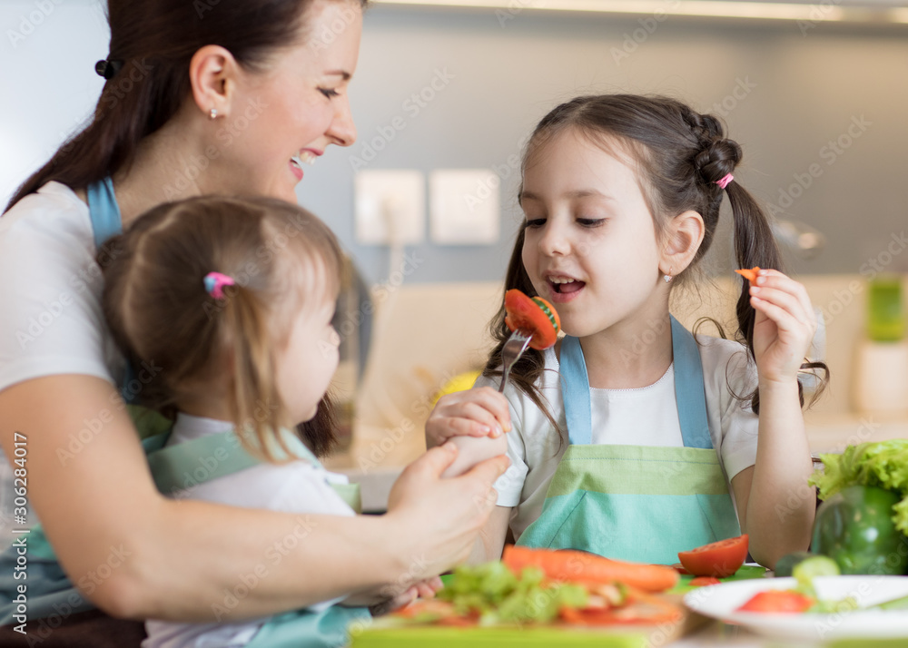Child tasting food during cooking with their mother and sister Child tasting food during cooking with their mother and sister