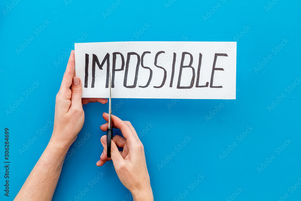 All is possible concept. Hands cut word impossible on blue background All is possible concept. Hands cut word impossible on blue background