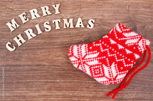 Inscription Merry Christmas with festive red sock on rustic board