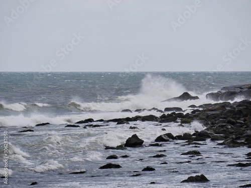 Wide shot of rocky shoreline with waves breaking against the rocks