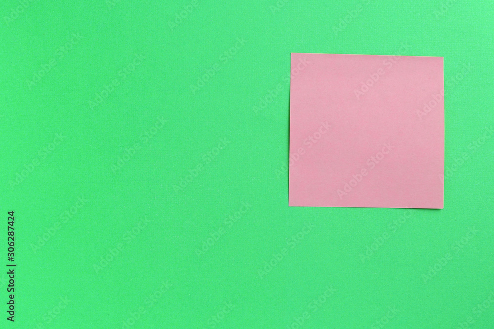 Empty pink sticker note on a green background. Business concept, horizontal mock-up Empty pink sticker note on a green background. Business concept, horizontal mock-up