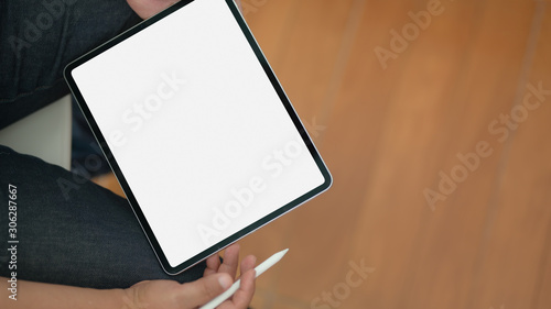 Fototapeta Naklejka Na Ścianę i Meble -  Close-up view of man using blank screen digital tablet while sitting in his office room