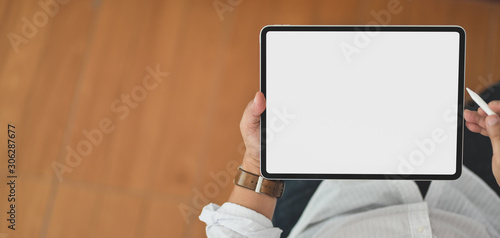 Close-up view of young man using blank screen digital tablet while sitting in his office room