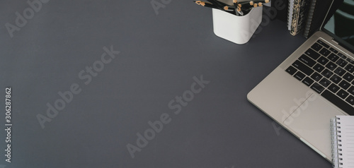 Top view of modern workplace with laptop computer and office supplies on dark grey table photo