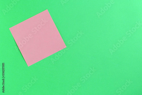 Empty pink sticker note on a green background. Business concept, horizontal mock-up