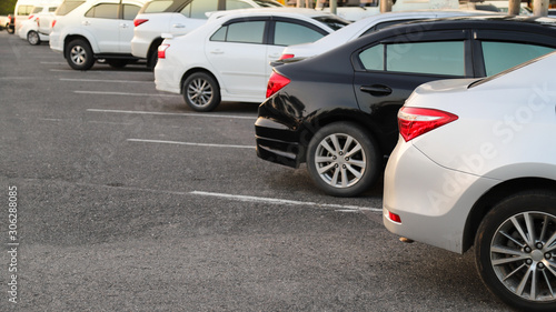 Closeup of rear, back side of bronze car with other cars parking in outdoor parking area