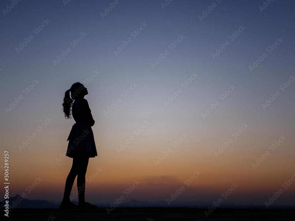 Fototapeta premium silhouette of young woman freedom feeling at sunset,thinking