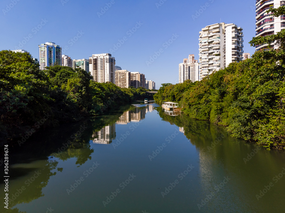Aerial view of Marapendi canal in Barra da Tijuca on a summer day. Tall residential skyscrapers on both sides, with green vegetation
