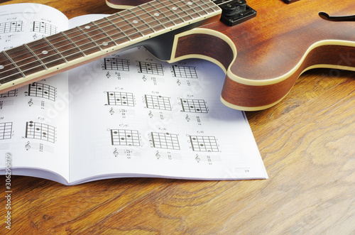Electric guitar and chord book on a wooden texture