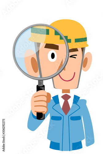 青い作業着の工事現場の男性が虫眼鏡でチェックする