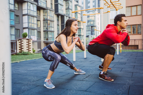Young couple in black sports outfit doing morning workout outdoors. Young man and woman stretching they muscle before running on bridge.