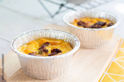 Bread pudding with black rasins in round foil cup on wooden tray. Delicious custard for coffee times. photo