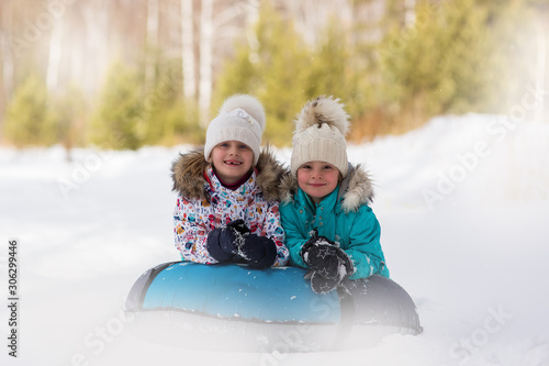 Joyful girls ride a tubing from a hill together. Winter holiday.