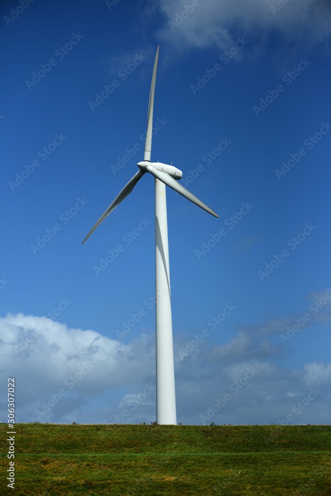 Wind Turbine on grassy field against blue sky Wind Turbine on grassy field against blue sky