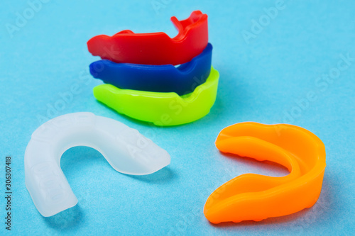 many colored boxing mouth guards lie on a blue background, concept photo