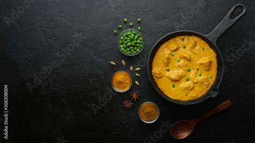 Cooking tasty chicken curry in pan on black background. Flat lay, top view with copy space photo
