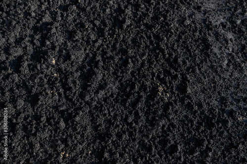 Crumble Rough Black sand texture on the beach with sunset light on surface, mix with normal sand look like soil for planting