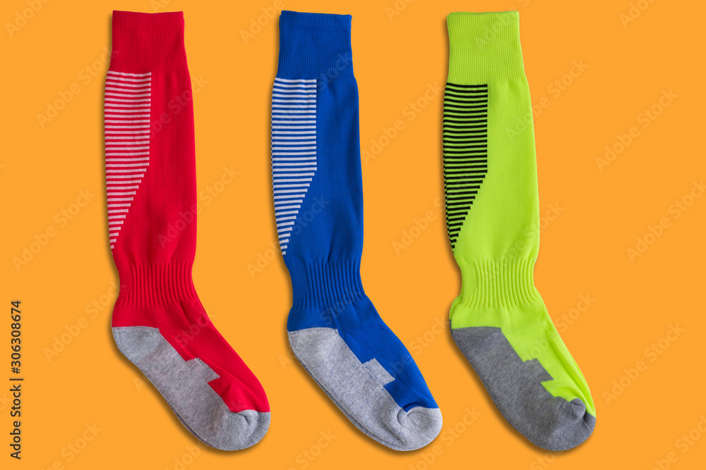 three pairs of colored football leggings lie on a yellow background, red, blue and green three pairs of colored football leggings lie on a yellow background, red, blue and green