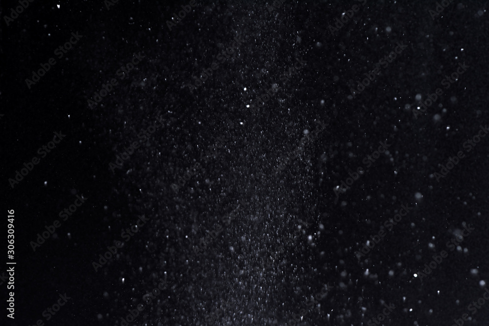 Fototapeta premium Falling snow at night. Bokeh lights on black background, flying snowflakes in the air. Overlay texture. Snowstorm