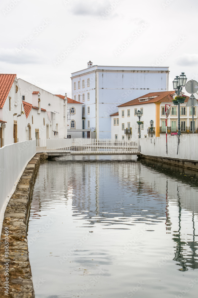 View of a river on Tomar city downtown, pedestrian bridge and buildings on banks, Portugal