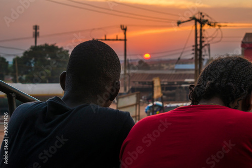young black man and lady sitting together outside having a conversation and watching the evening sunset