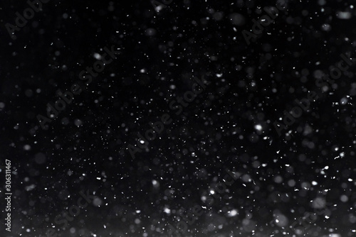 Falling  snow at night. Bokeh lights on black background, flying snowflakes in the air. Overlay texture. Snowstorm photo