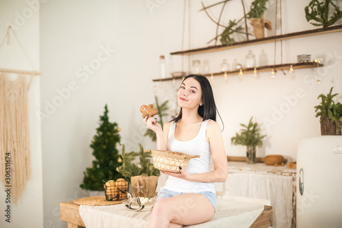 Young woman in the kitchen before the new year. Girl is preparing gingerbread cookie for Christmas. Textural kitchen in bright colors.