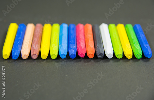 front view of set of random crayon colors focus on a black chart background