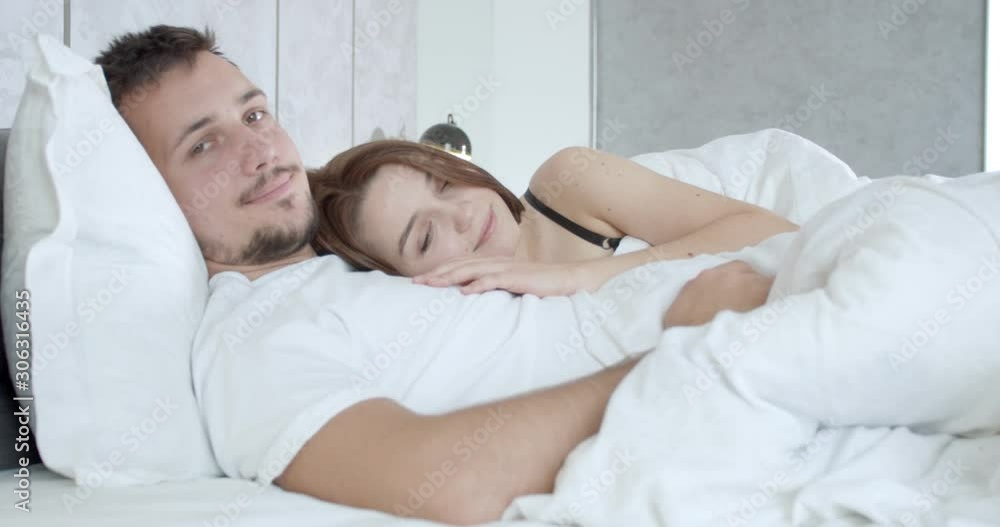 Cute young couple is lying in bed, woman is resting on the mans chest, 4k Cute young couple is lying in bed, woman is resting on the mans chest, 4k