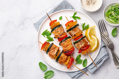 Grilled salmon and vegetables skewers on white plate