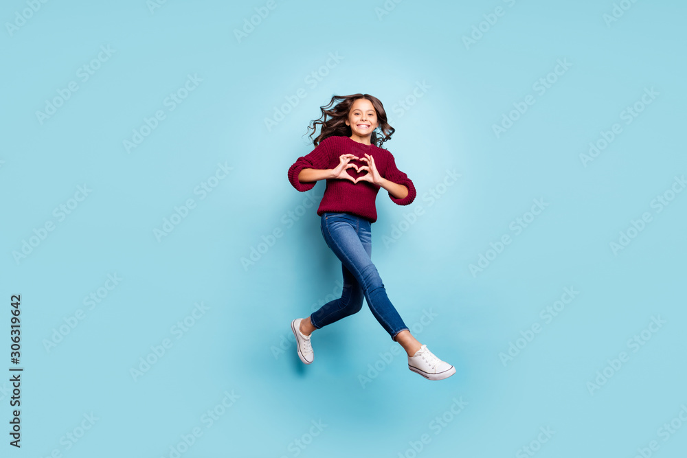 Full length body size photo of cheerful positive girlfriend jumping running showing heart sign wearing jeans denim burgundy sweater isolated blue vivid color background