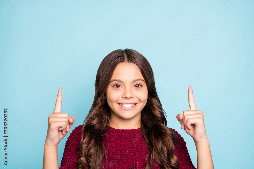 Close up photo of cheerful positive toothy beaming preteen pointing up wavy to draw you attention to sales isolated vivid blue color background Close up photo of cheerful positive toothy beaming preteen pointing up wavy to draw you attention to sales isolated vivid blue color background