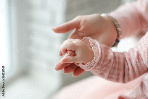Newborn baby holds mom by the finger.Tiny newborn infant male or female baby hand holding mother finger. Mother holding her newborn child. Family maternity, tenderness, parenthood, responsibility conc