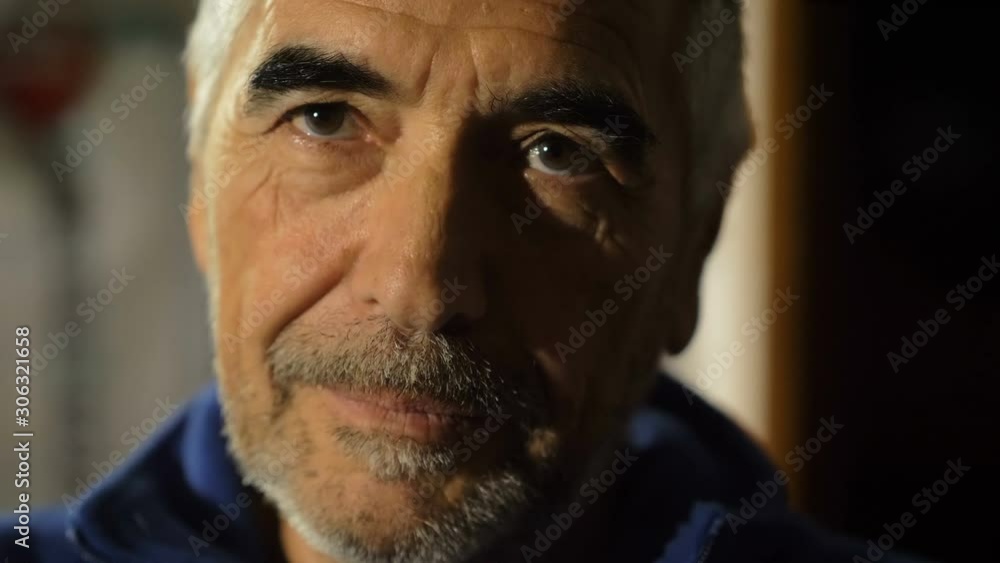 Relaxed handsome mature man looking at camera in the dark-indoor Relaxed handsome mature man looking at camera in the dark-indoor